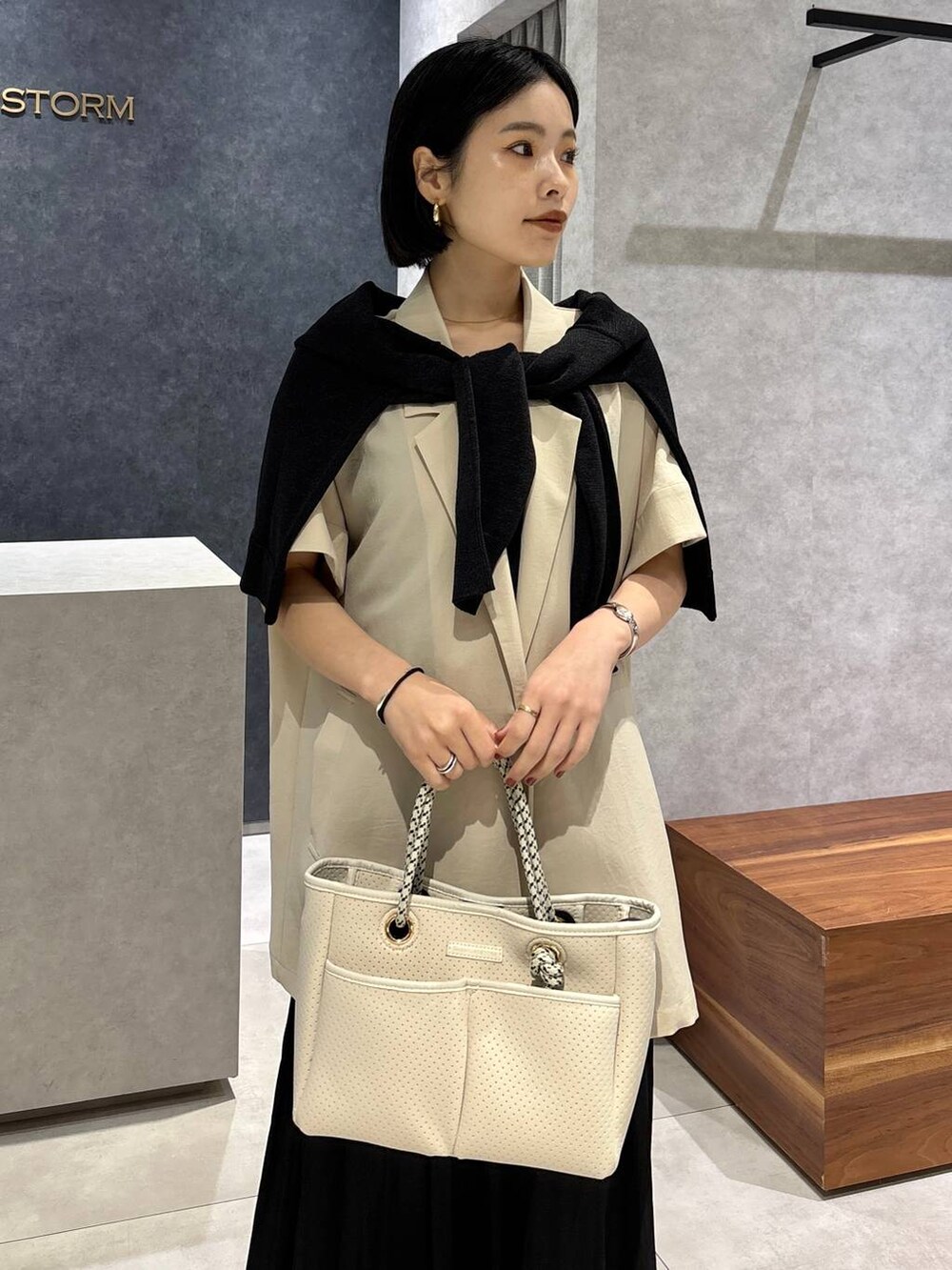 ブラック系のトートバッグ、ベージュ系のテーラードジャケット、ブラック系のサンダルを着用したレディースの春コーディネートの5枚目の写真