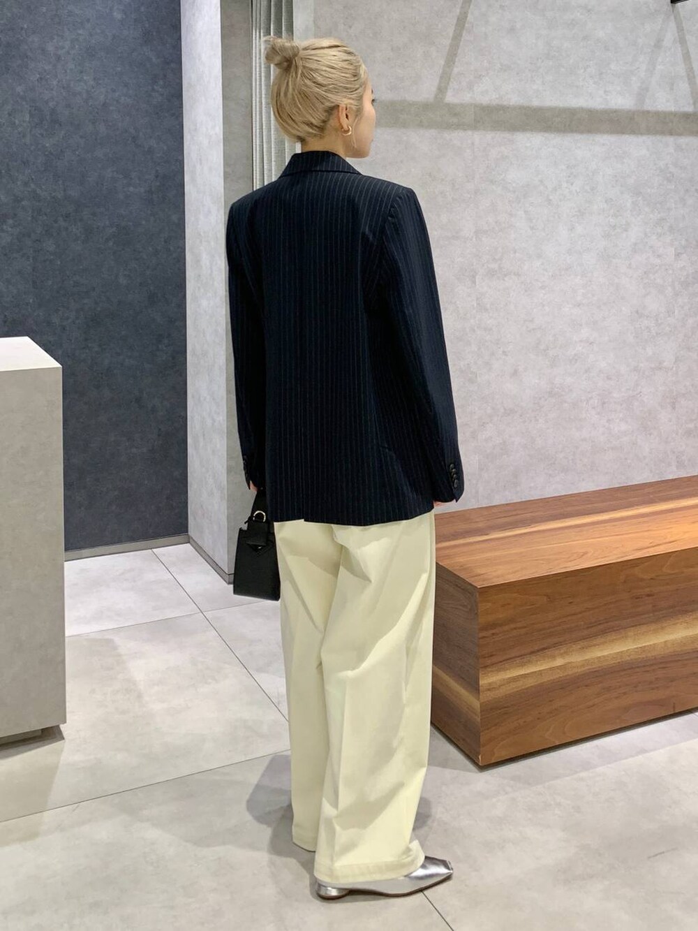 ブラック系のハンドバッグ、シルバー系のパンプス、ブルー系のニット/セーターを着用したレディースの秋コーディネートの3枚目の写真