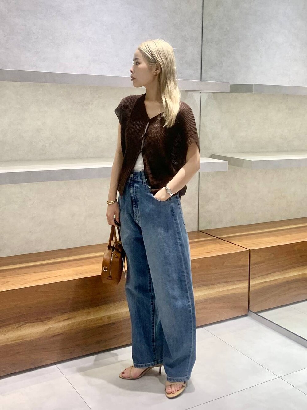 ベージュ系のスリッポン、ブラウン系のハンドバッグ、ブルー系のデニムパンツを着用したレディースの夏コーディネートの2枚目の写真