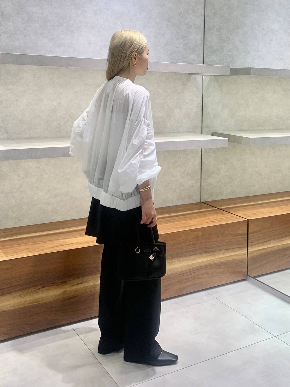 ブラック系のセットアップ、ホワイト系のブルゾン、ブラック系のパンプスを着用したレディースの夏コーディネートの2枚目の写真