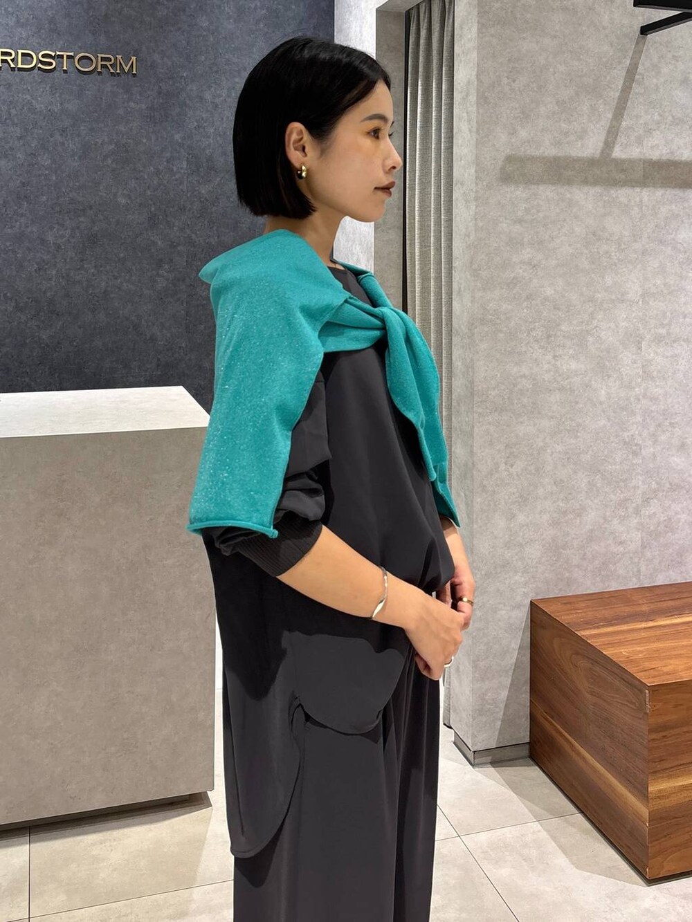 グレー系のシャツ/ブラウス、グレー系のスラックス、グリーン系のニット/セーターを着用したレディースの夏コーディネートの7枚目の写真