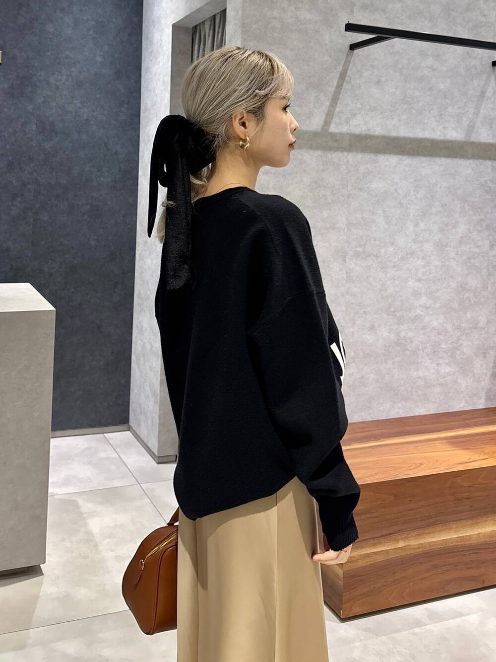 イエロー系のボストンバッグ、ブラック系のローファー、ブラック系のニット/セーターを着用したレディースの冬コーディネートの4枚目の写真