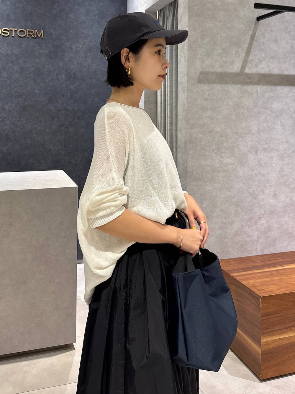 ブルー系のデニムパンツ、ブルー系のトートバッグ、ホワイト系のニット/セーターを着用したレディースの夏コーディネートの5枚目の写真