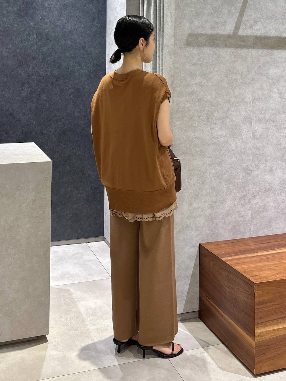 ブラウン系のハンドバッグ、ブラック系のサンダル、イエロー系のニット/セーターを着用したレディースの夏コーディネートの2枚目の写真