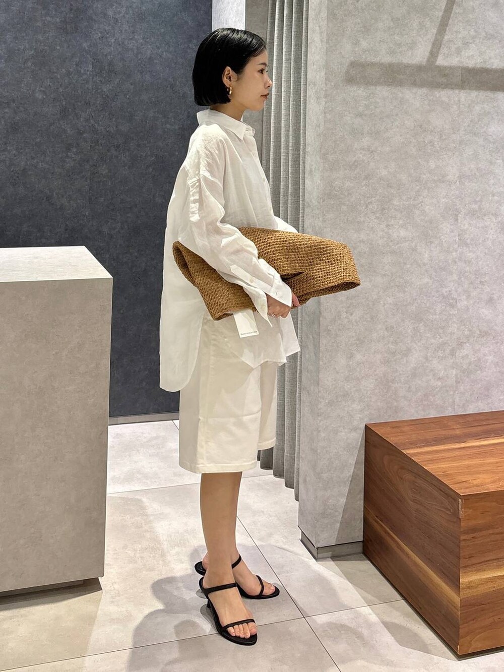 ブラウン系のトートバッグ、ブラック系のサンダル、ホワイト系のシャツ/ブラウスを着用したレディースの春コーディネートの3枚目の写真