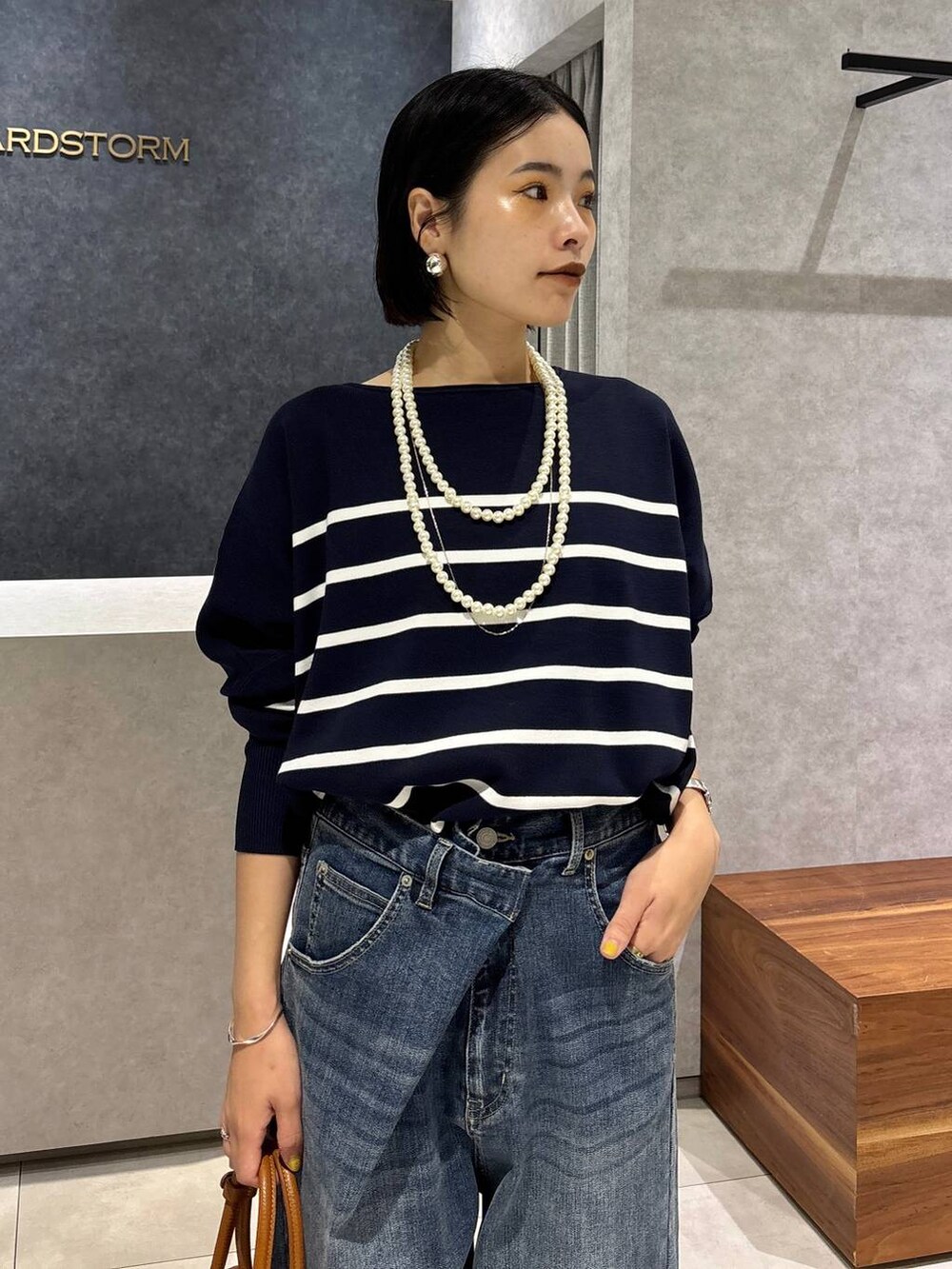 ブルー系のデニムパンツ、イエロー系のハンドバッグ、ブルー系のニット/セーターを着用したレディースの夏コーディネートの4枚目の写真