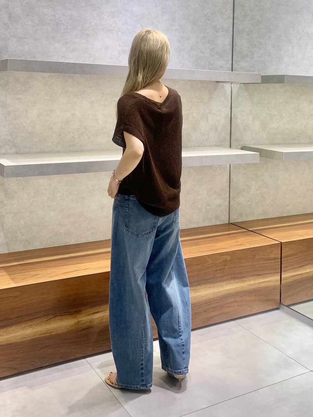 ベージュ系のスリッポン、ブラウン系のハンドバッグ、ブルー系のデニムパンツを着用したレディースの夏コーディネートの3枚目の写真