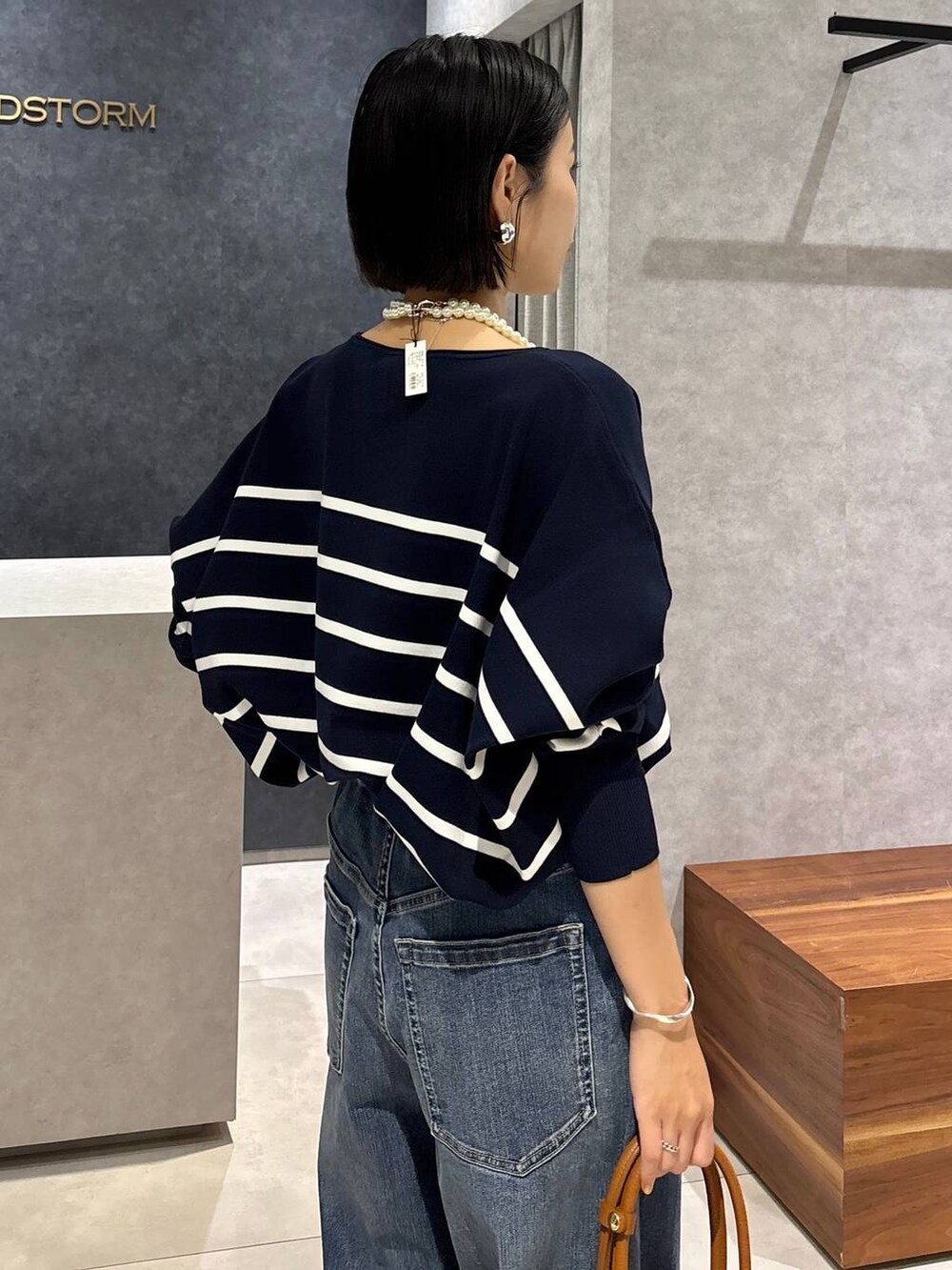 ブルー系のデニムパンツ、イエロー系のハンドバッグ、ブルー系のニット/セーターを着用したレディースの夏コーディネートの6枚目の写真