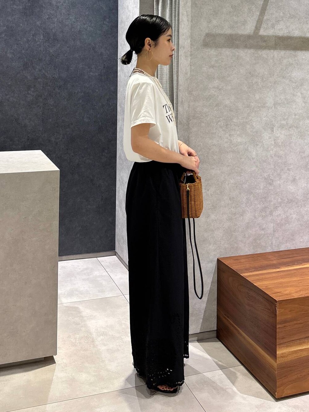 ブラック系のショルダーバッグ、ブラック系のサンダル、ホワイト系のTシャツ/カットソーを着用したレディースの夏コーディネートの2枚目の写真