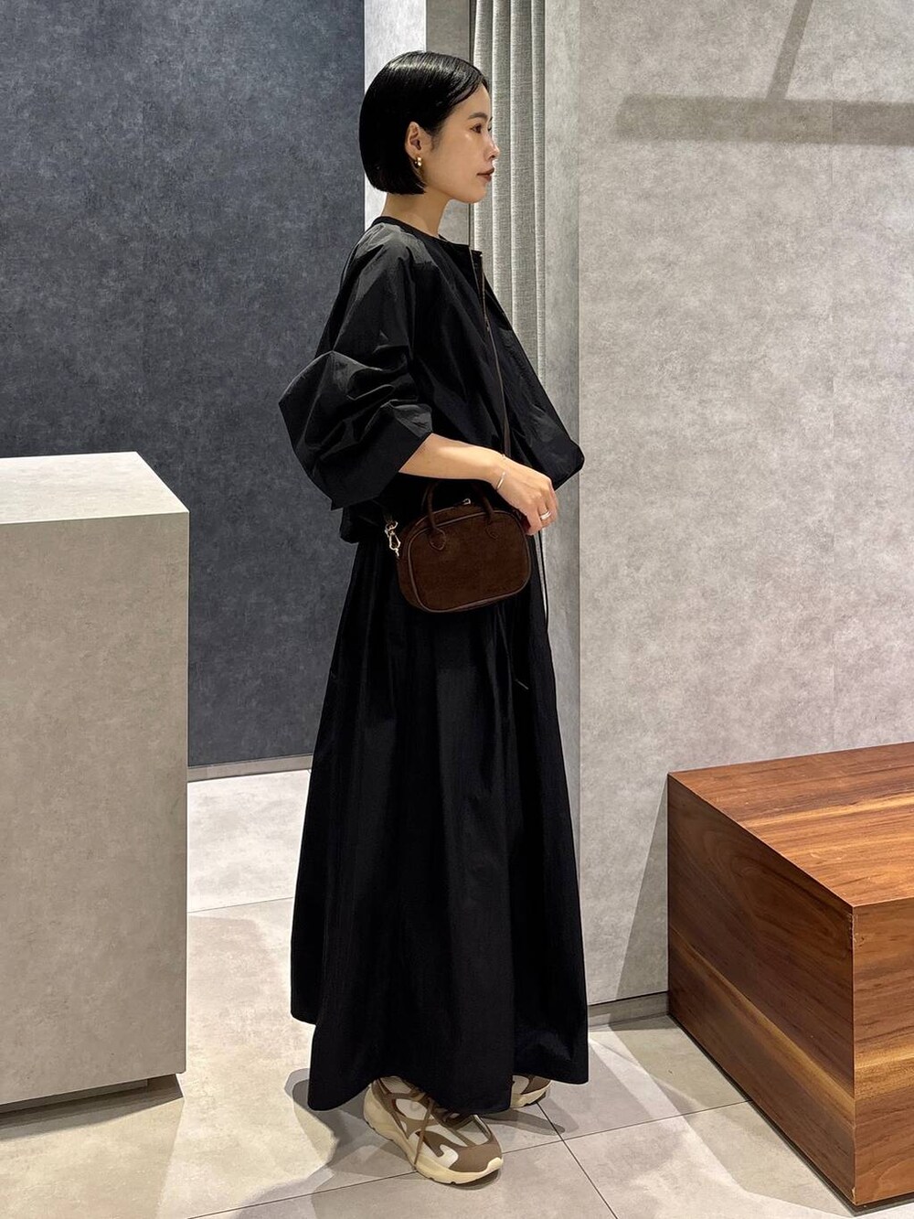 ブラック系のスカート、ブラック系のブルゾン、ブラウン系のショルダーバッグを着用したレディースの夏コーディネートの2枚目の写真