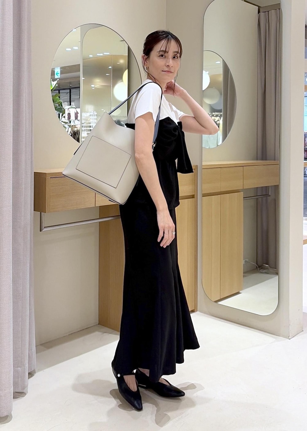 ベージュ系のトートバッグ、ブラック系のパンプス、ブラック系のTシャツ/カットソーを着用したレディースの春コーディネートの2枚目の写真