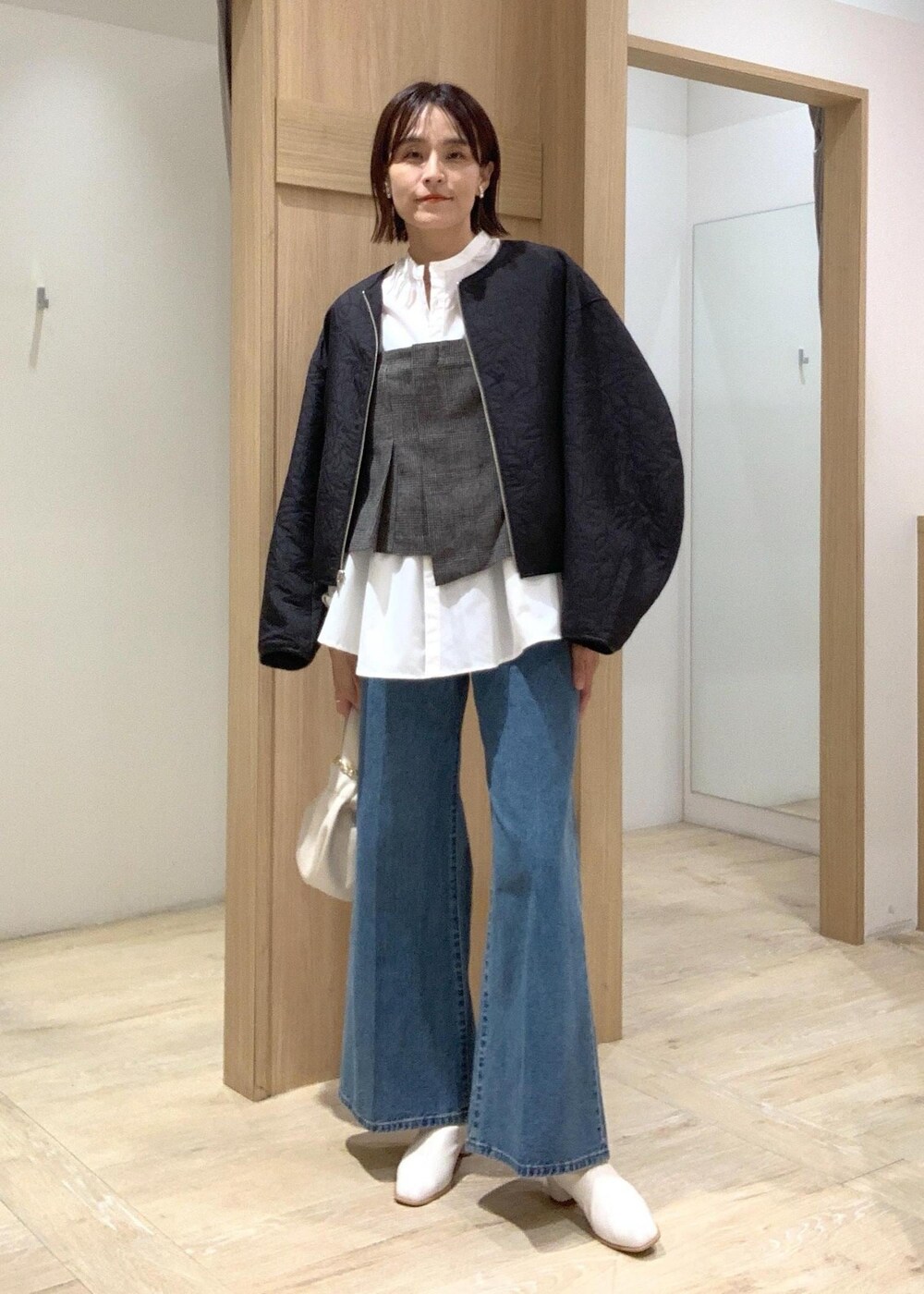 ホワイト系のハンドバッグ、ブルー系のデニムパンツ、ホワイト系のブーツを着用したレディースの秋コーディネートの8枚目の写真