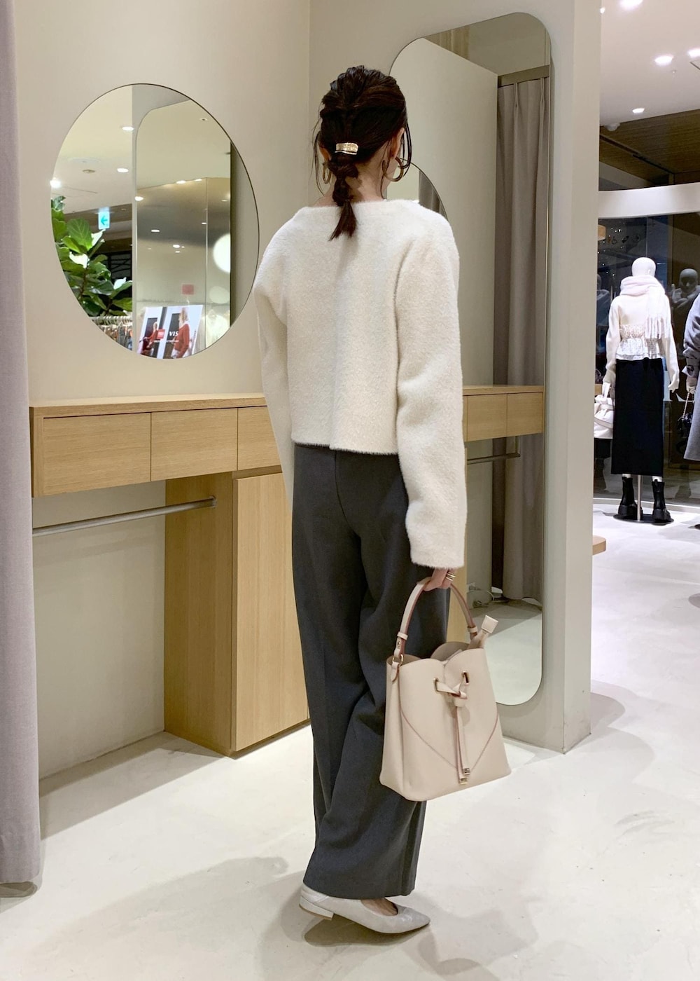 ベージュ系のショルダーバッグ、グレー系のスラックス、ホワイト系のカーディガン/ボレロを着用したレディースの冬コーディネートの3枚目の写真