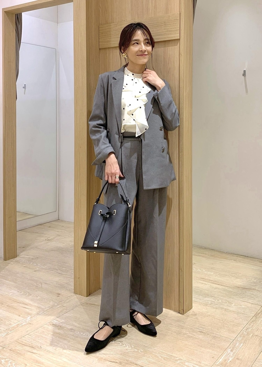 ブラック系のショルダーバッグ、グレー系のスラックス、グレー系のテーラードジャケットを着用したレディースの冬コーディネートの2枚目の写真