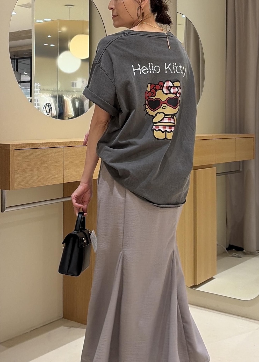 ブラック系のショルダーバッグ、グレー系のスカート、ブラック系のサンダルを着用したレディースの夏コーディネートの9枚目の写真