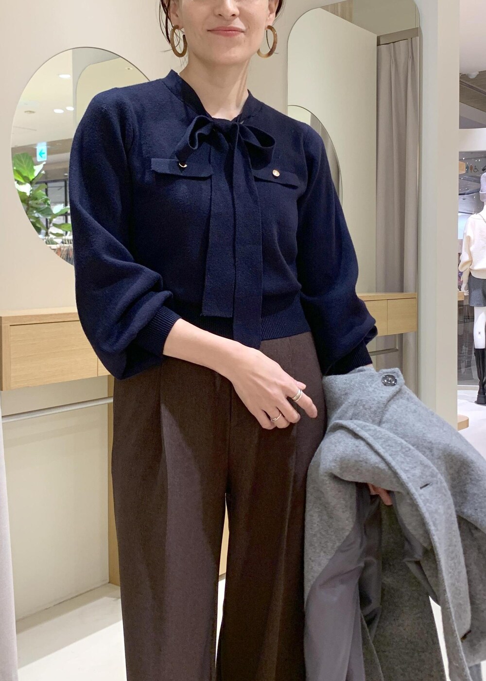 ブルー系のハンドバッグ、ブラウン系のスラックス、グレー系のその他アウターを着用したレディースの冬コーディネートの6枚目の写真