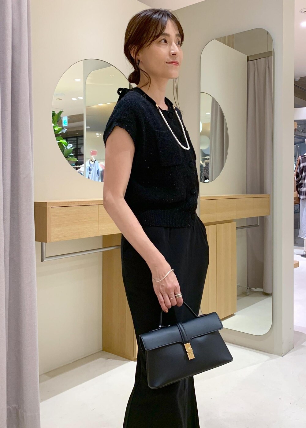 ブラック系のショルダーバッグ、ブラック系のカーディガン/ボレロ、ブラック系のキャミソールを着用したレディースの夏コーディネートの5枚目の写真