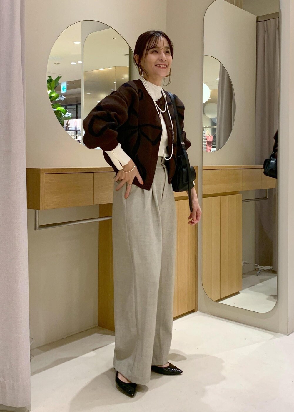 ブラック系のショルダーバッグ、ベージュ系のその他パンツ、ブラウン系のカーディガン/ボレロを着用したレディースの秋コーディネートの2枚目の写真