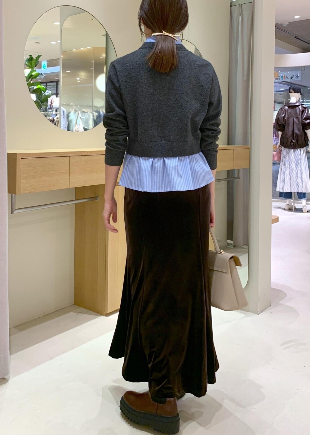 ベージュ系のハンドバッグ、ブラウン系のブーツ、ブラウン系のスカートを着用したレディースの秋コーディネートの4枚目の写真