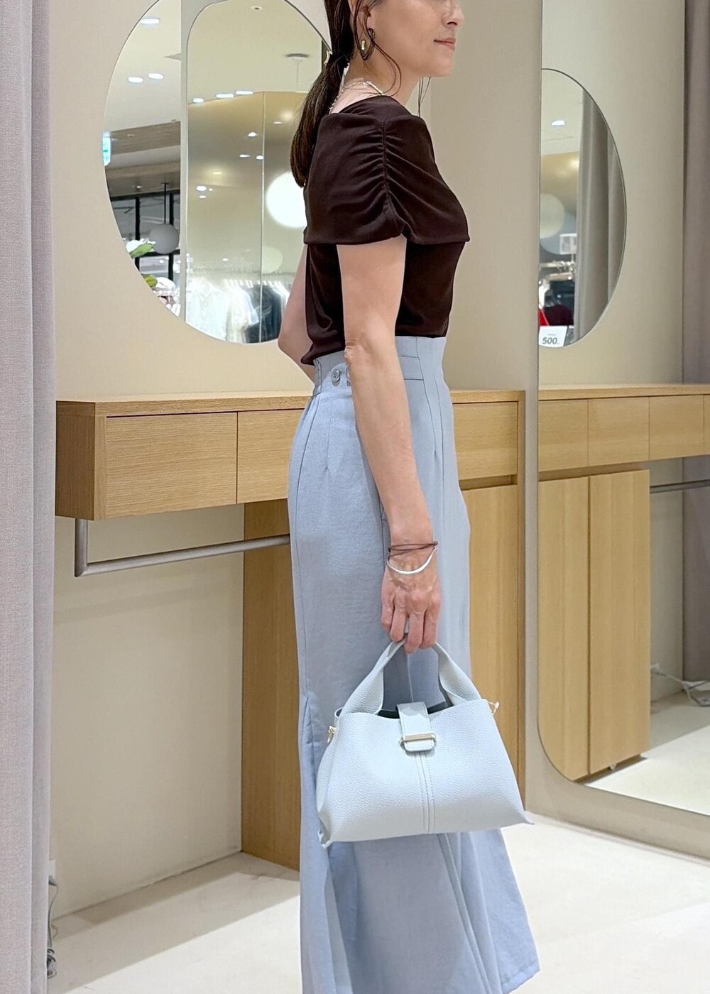 ホワイト系のサンダル、ブルー系のスカート、ブラウン系のTシャツ/カットソーを着用したレディースの夏コーディネートの6枚目の写真