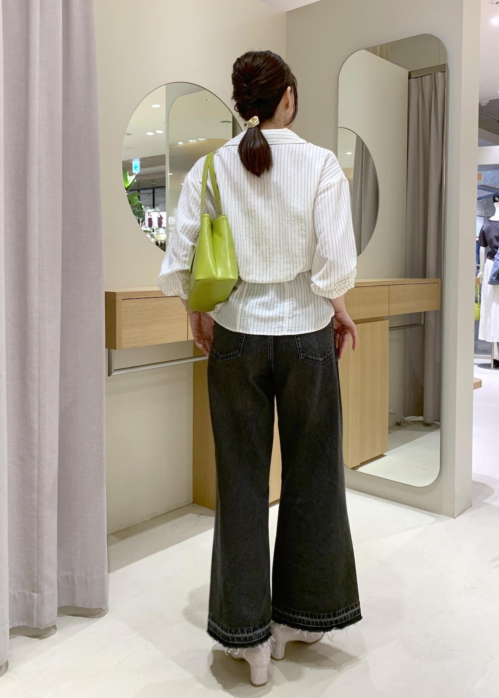 ホワイト系のキャミソール、ベージュ系のパンプス、ブラック系のデニムパンツを着用したレディースの春コーディネートの4枚目の写真