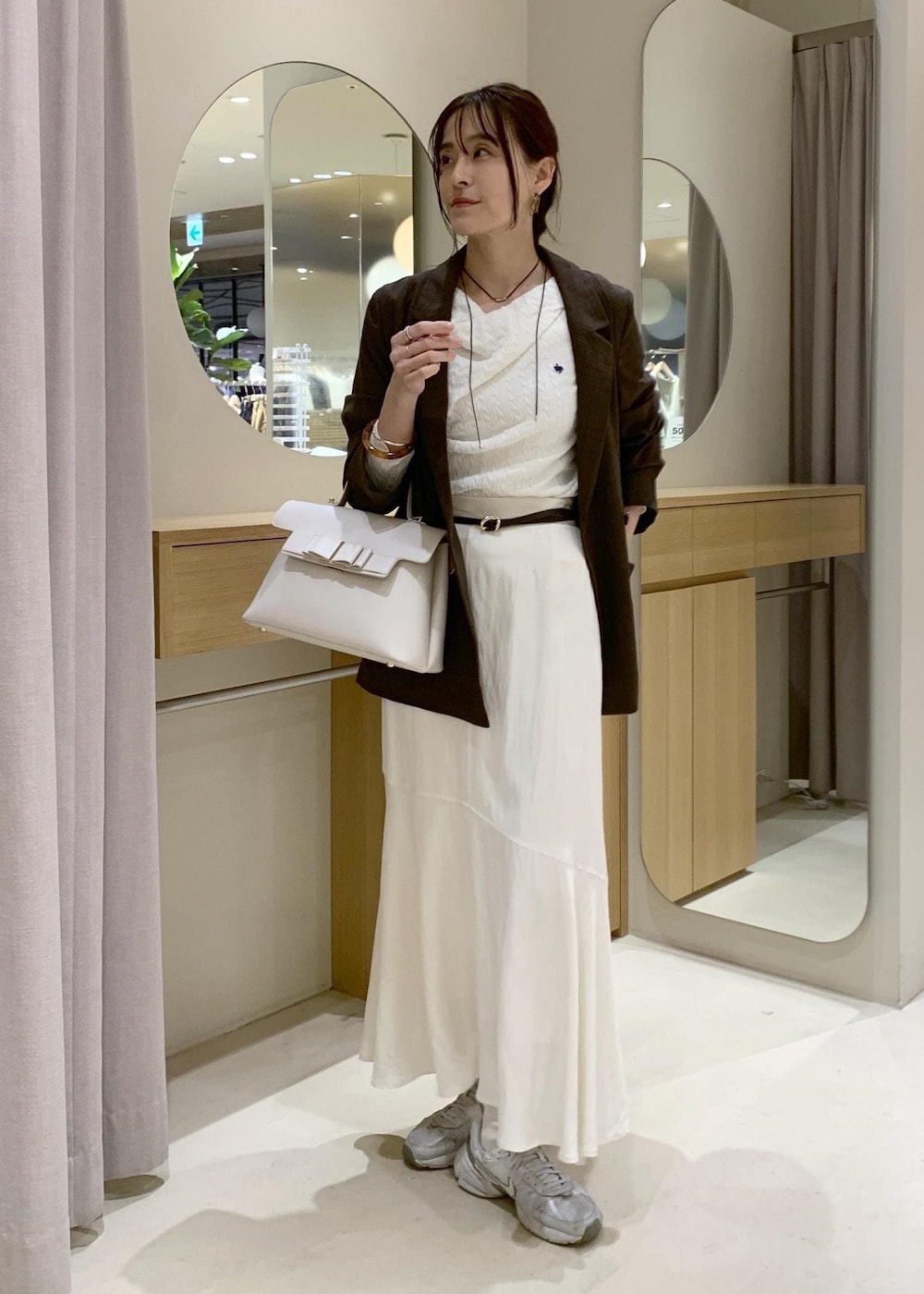 ホワイト系のハンドバッグ、ホワイト系のスカート、ホワイト系のニット/セーターを着用したレディースの春コーディネートの2枚目の写真