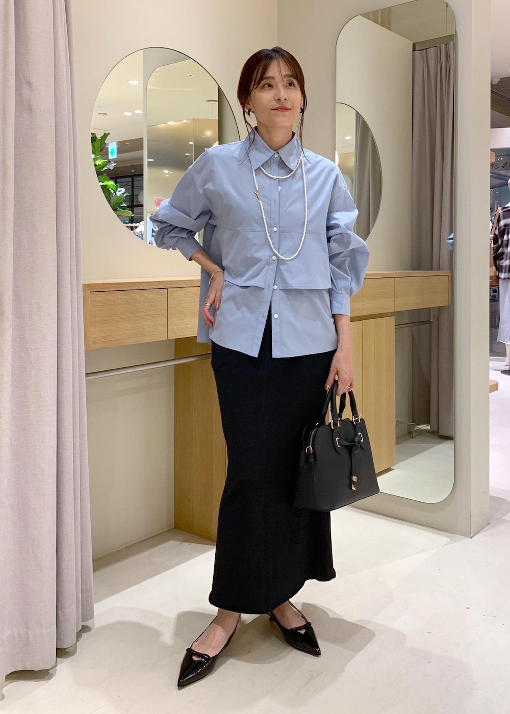 ブラック系のパンプス、ブラック系のスカート、ブルー系のシャツ/ブラウスを着用したレディースの夏コーディネートの2枚目の写真