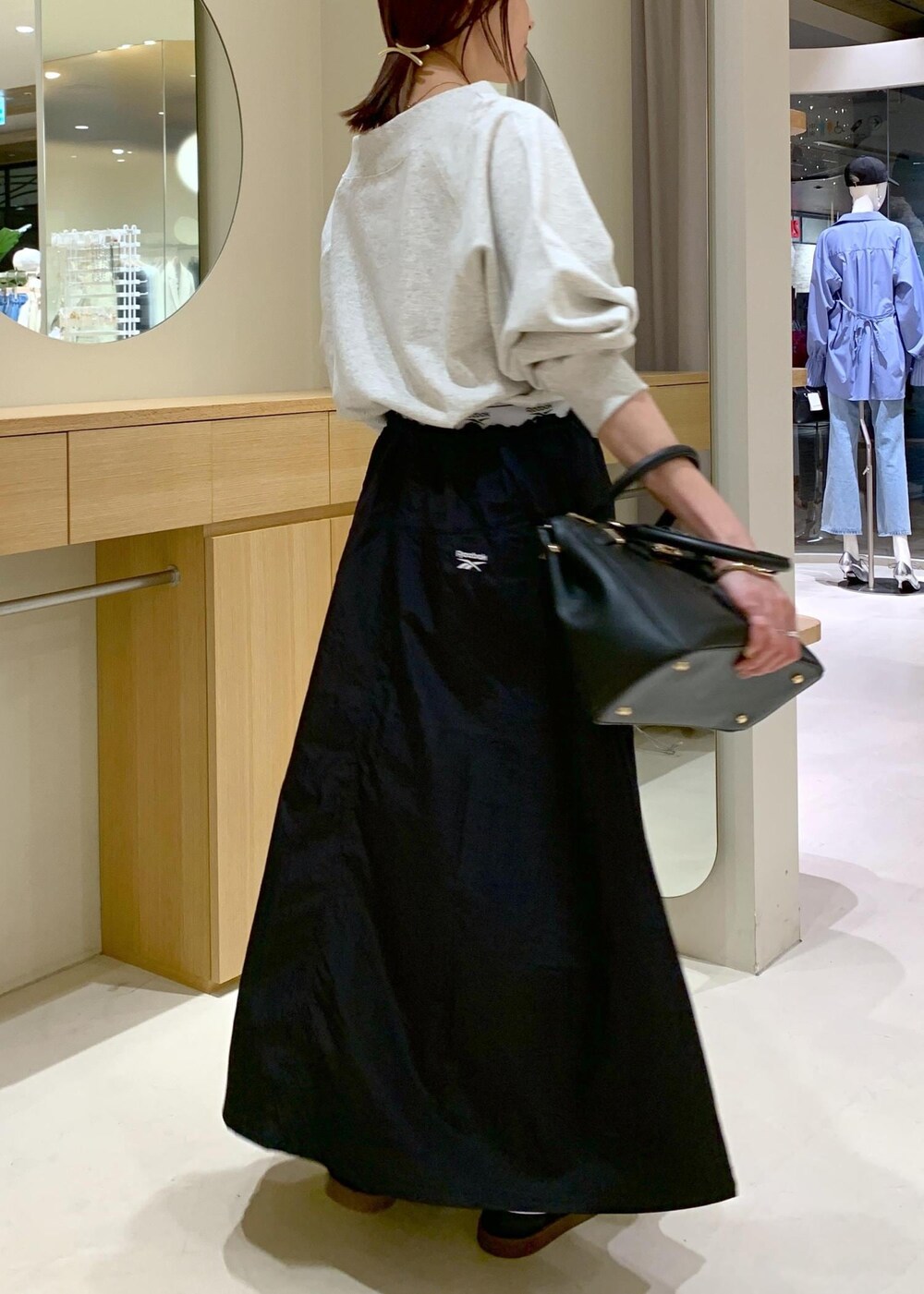 ブラック系のキャミソール、ブルー系のスカート、ホワイト系のスウェットを着用したレディースの春コーディネートの8枚目の写真