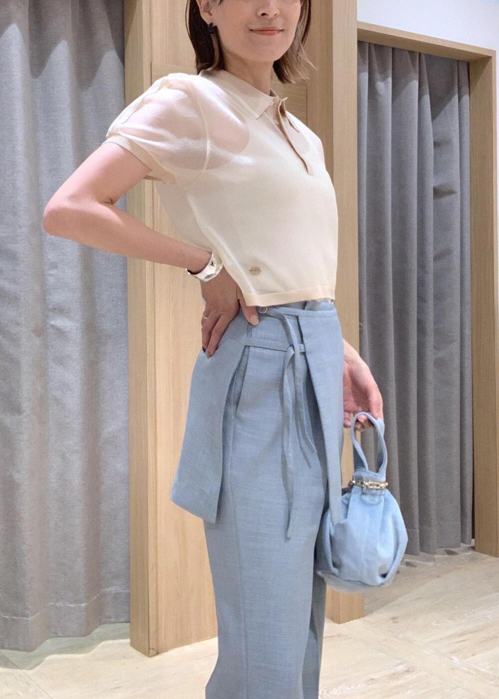 ホワイト系のサンダル、ブルー系のスラックス、ブルー系のハンドバッグを着用したレディースの夏コーディネートの5枚目の写真