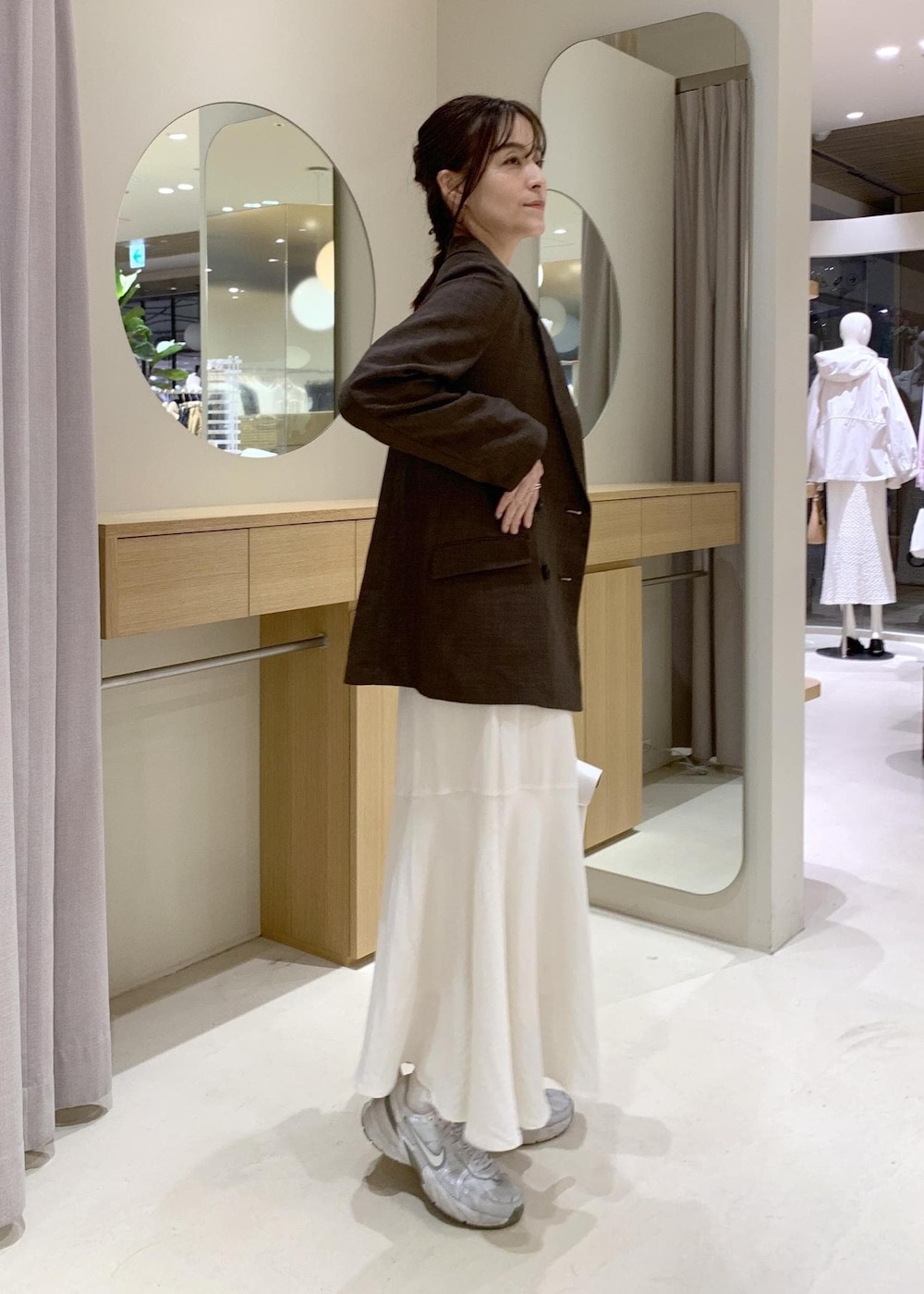 ホワイト系のハンドバッグ、ホワイト系のスカート、ホワイト系のニット/セーターを着用したレディースの春コーディネートの3枚目の写真