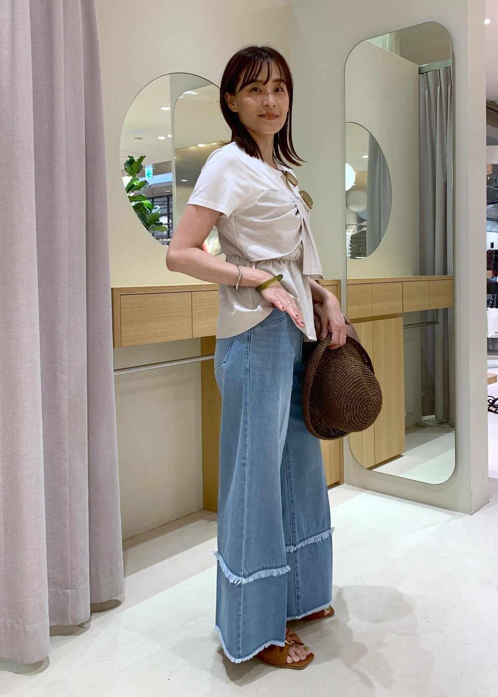 イエロー系のサンダル、ホワイト系のTシャツ/カットソー、ブルー系のデニムパンツを着用したレディースの夏コーディネートの3枚目の写真