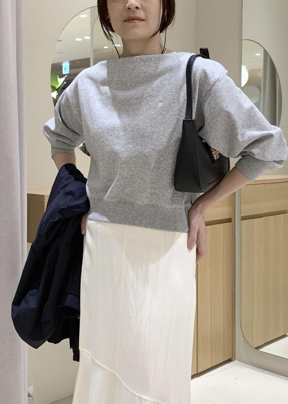 ブラック系のショルダーバッグ、ブルー系のナイロンジャケット、ホワイト系のキャミソールを着用したレディースの春コーディネートの9枚目の写真