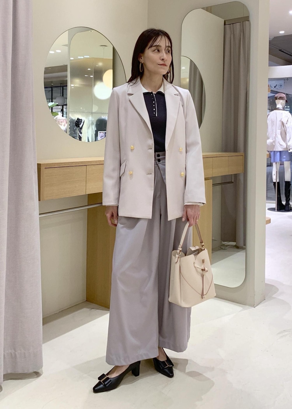ベージュ系のショルダーバッグ、ブラック系のパンプス、ベージュ系のテーラードジャケットを着用したレディースの春コーディネートの2枚目の写真