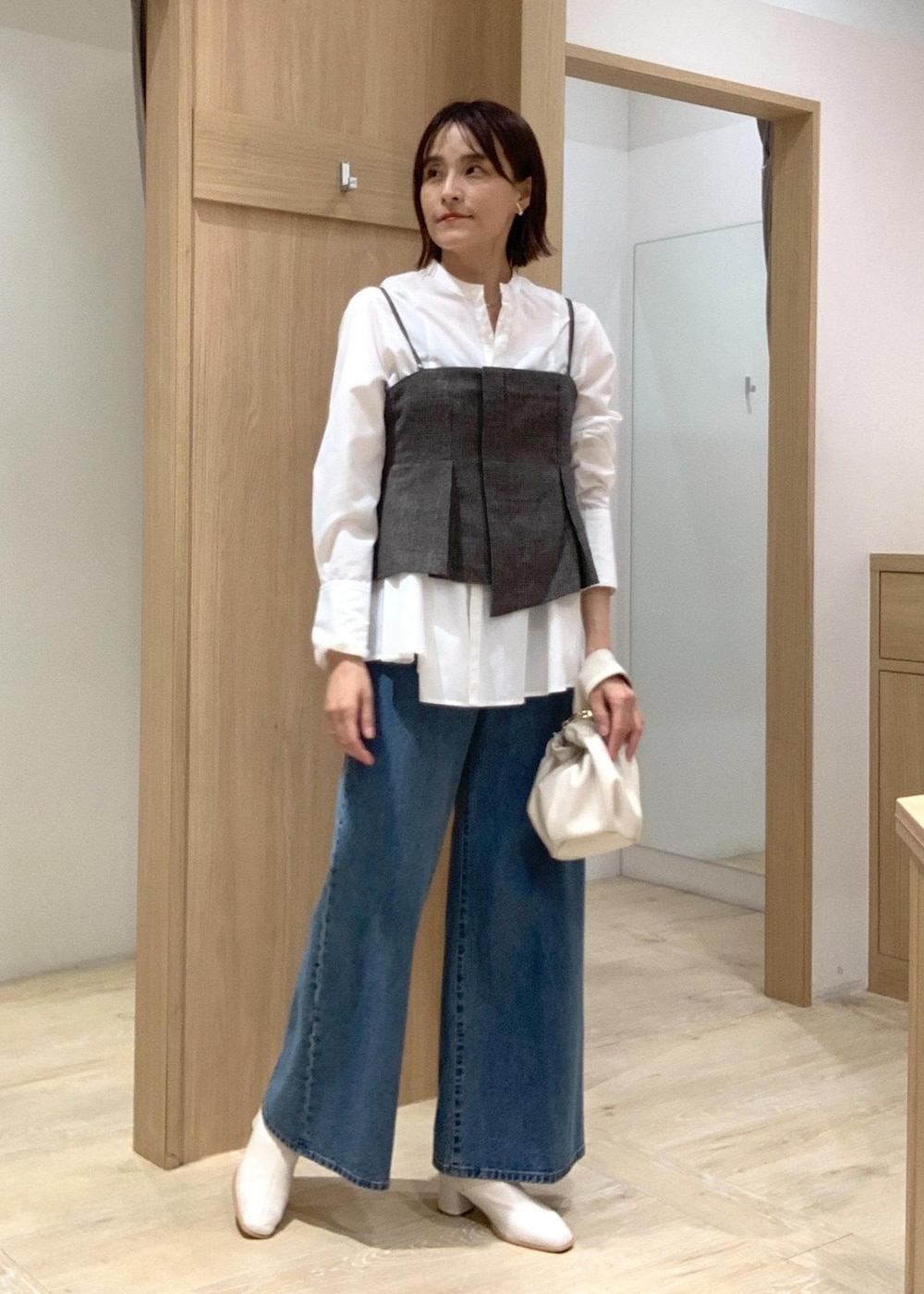 ホワイト系のハンドバッグ、ブルー系のデニムパンツ、ホワイト系のブーツを着用したレディースの秋コーディネートの4枚目の写真