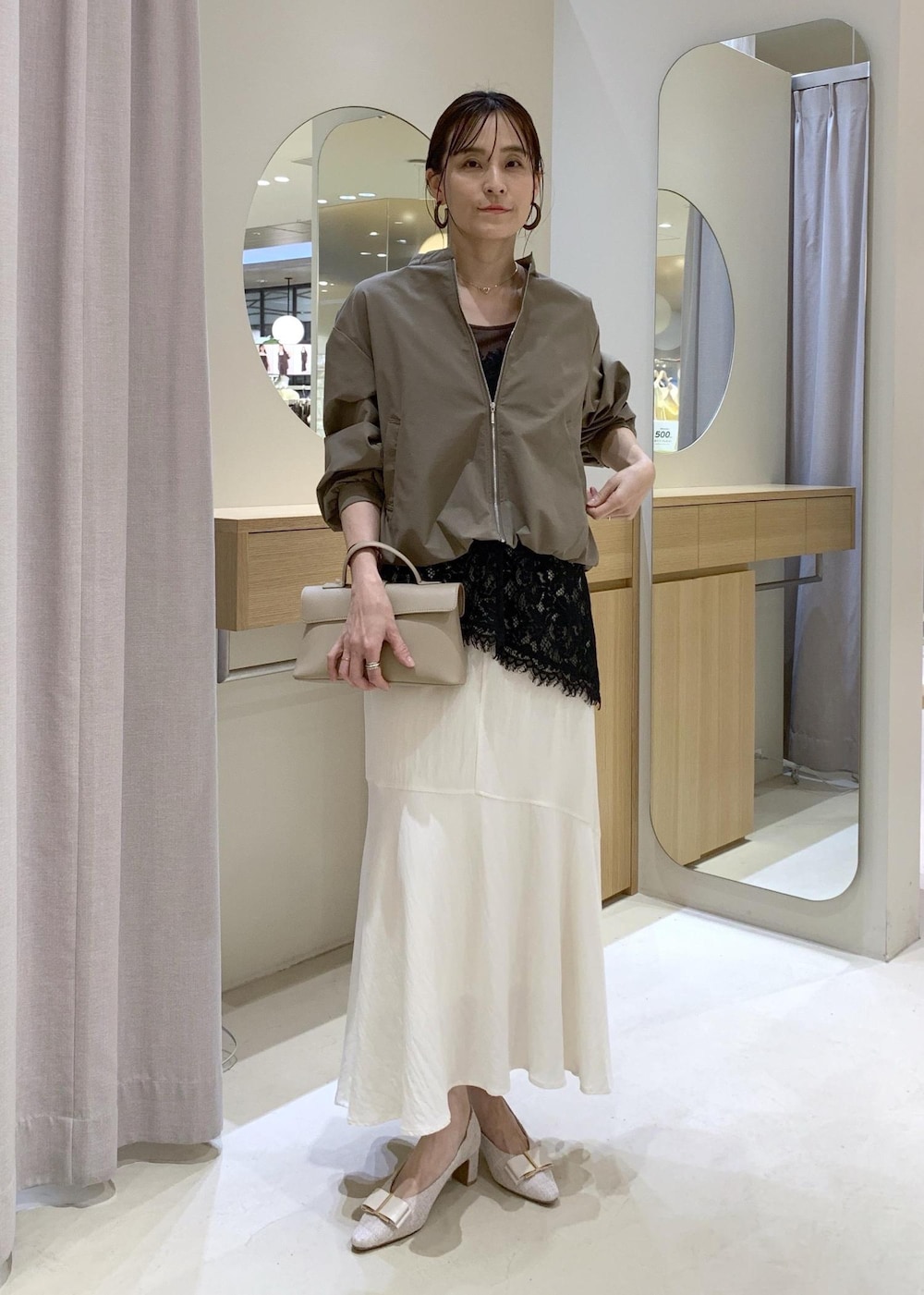 ベージュ系のパンプス、ホワイト系のスカート、ブラック系のキャミソールを着用したレディースの春コーディネートの2枚目の写真