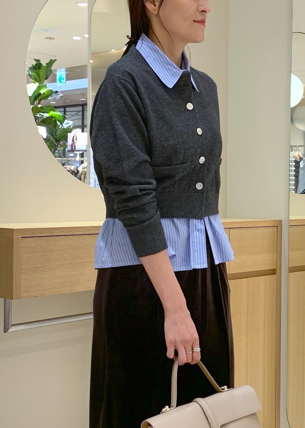 ベージュ系のハンドバッグ、ブラウン系のブーツ、ブラウン系のスカートを着用したレディースの秋コーディネートの6枚目の写真