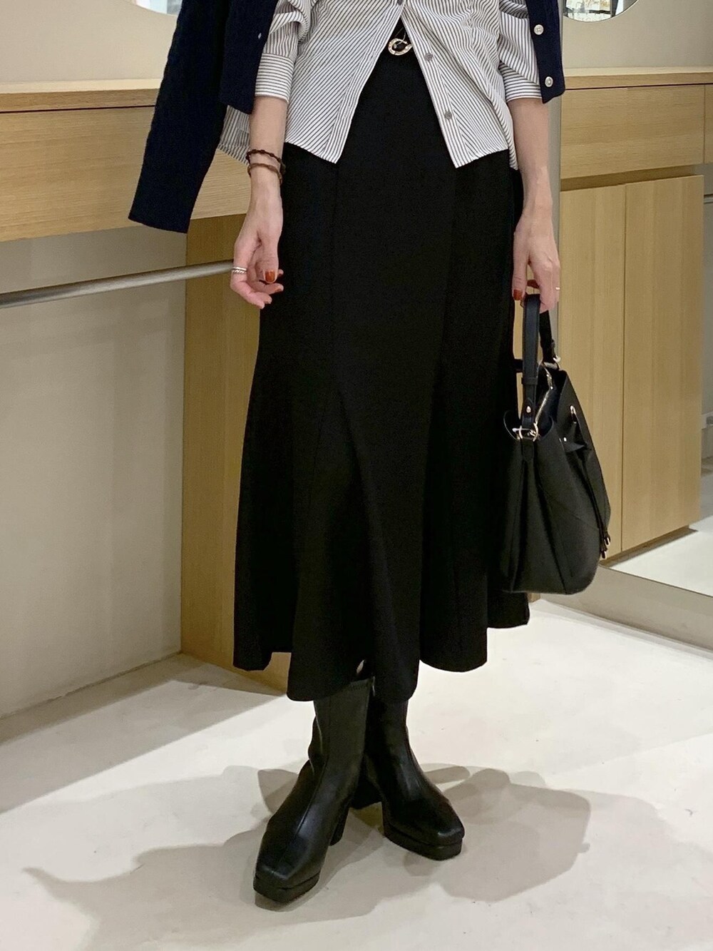 ブラック系のショルダーバッグ、ブラック系のスカート、ブルー系のカーディガン/ボレロを着用したレディースの秋コーディネートの8枚目の写真
