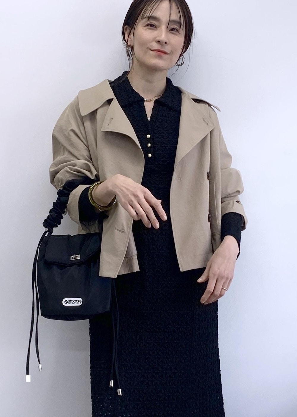 ブラック系のショルダーバッグ、ベージュ系のトレンチコート、ブルー系のデニムパンツを着用したレディースの冬コーディネートの4枚目の写真