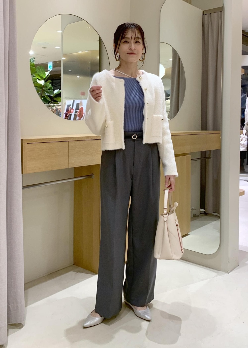 ベージュ系のショルダーバッグ、グレー系のスラックス、ホワイト系のカーディガン/ボレロを着用したレディースの冬コーディネートの2枚目の写真