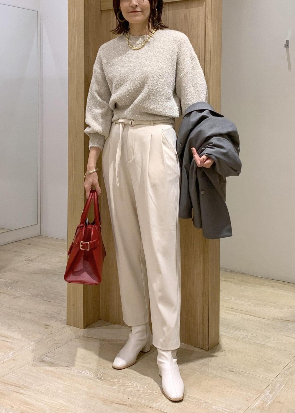 レッド系のトートバッグ、ホワイト系のブーツ、グレー系のテーラードジャケットを着用したレディースの冬コーディネートの7枚目の写真