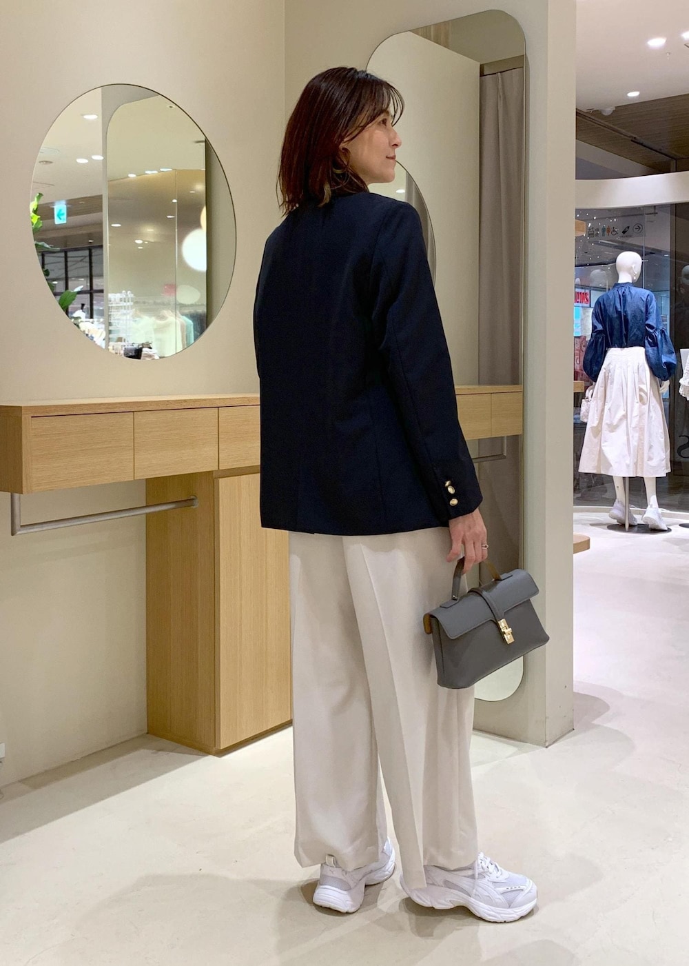 グレー系のショルダーバッグ、ホワイト系のニット/セーター、ブルー系のテーラードジャケットを着用したレディースの冬コーディネートの4枚目の写真