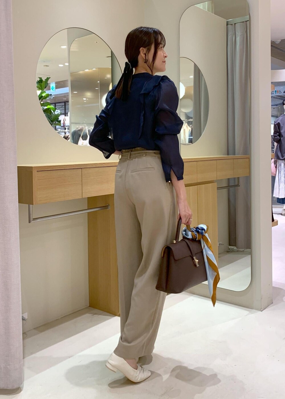 ブラウン系のハンドバッグ、ホワイト系のパンプス、ブルー系のシャツ/ブラウスを着用したレディースの秋コーディネートの4枚目の写真