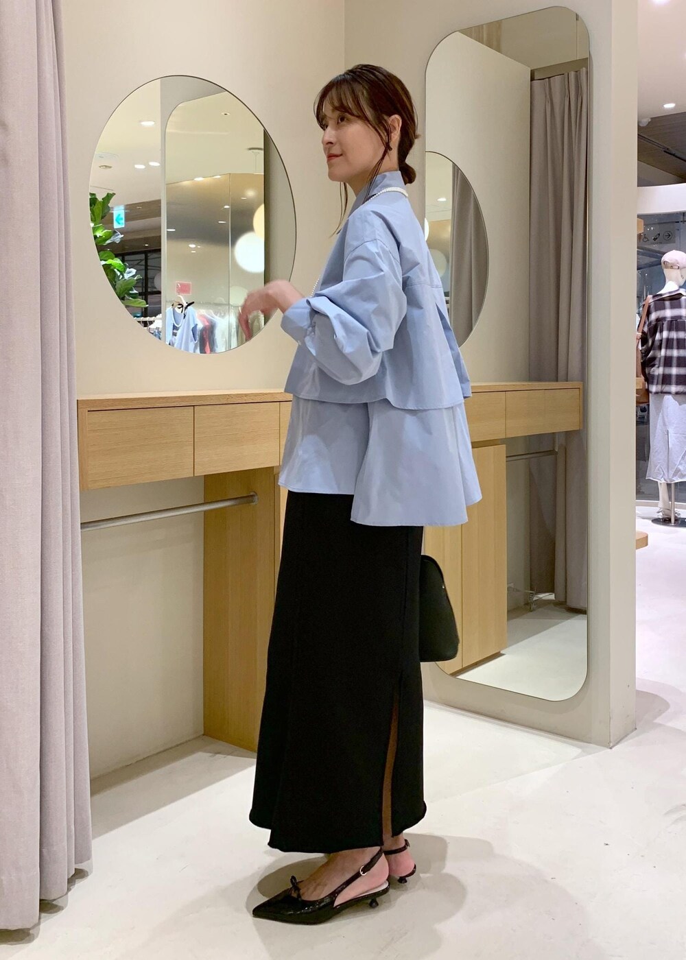 ブラック系のパンプス、ブラック系のスカート、ブルー系のシャツ/ブラウスを着用したレディースの夏コーディネートの3枚目の写真