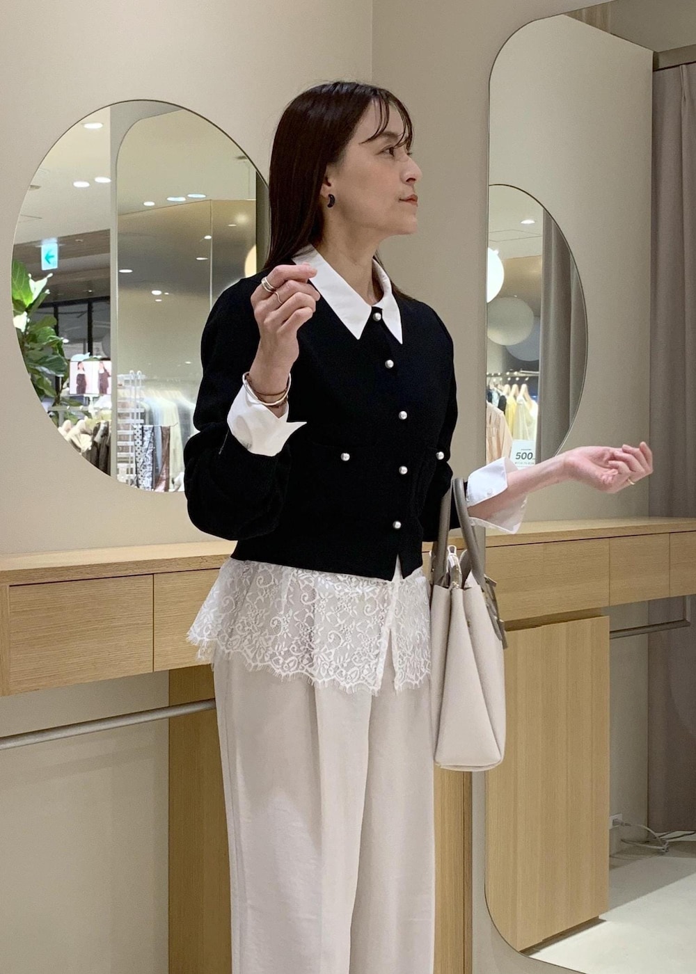 ベージュ系のパンプス、ホワイト系のシャツ/ブラウス、ブラック系のカーディガン/ボレロを着用したレディースの春コーディネートの3枚目の写真