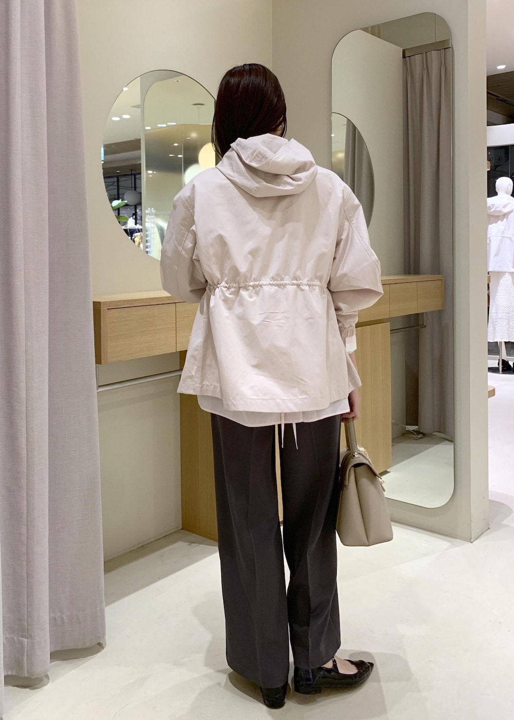 ベージュ系のハンドバッグ、ピンク系のナイロンジャケット、グレー系のスラックスを着用したレディースの春コーディネートの5枚目の写真