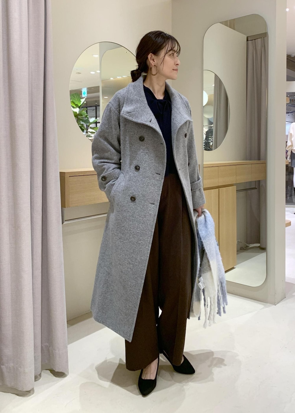 ブルー系のハンドバッグ、ブラウン系のスラックス、グレー系のその他アウターを着用したレディースの冬コーディネートの2枚目の写真