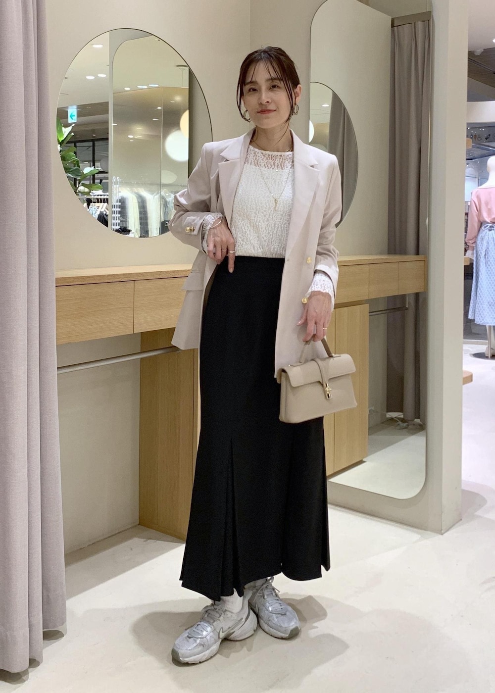 ブラック系のスカート、ホワイト系のTシャツ/カットソー、ベージュ系のテーラードジャケットを着用したレディースの冬コーディネートの2枚目の写真