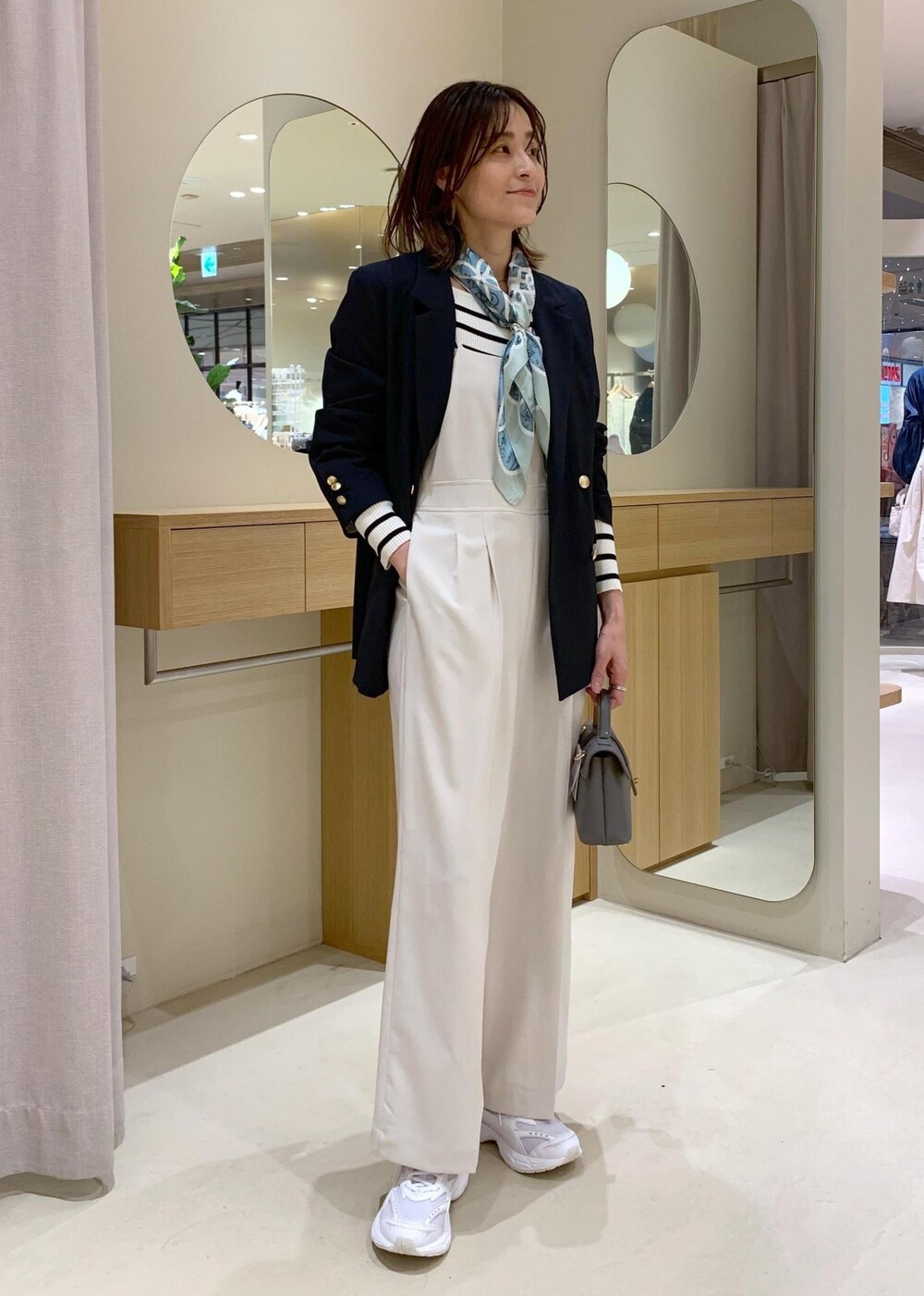 グレー系のショルダーバッグ、ホワイト系のニット/セーター、ブルー系のテーラードジャケットを着用したレディースの冬コーディネートの2枚目の写真