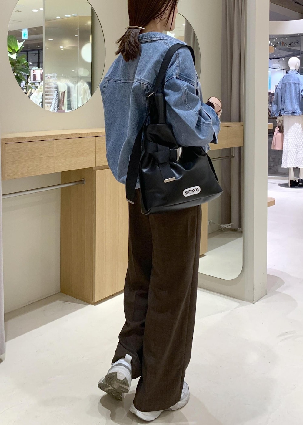 ブルー系のデニムジャケット、ブラック系のトートバッグ、ブラウン系のカーディガン/ボレロを着用したレディースの春コーディネートの3枚目の写真