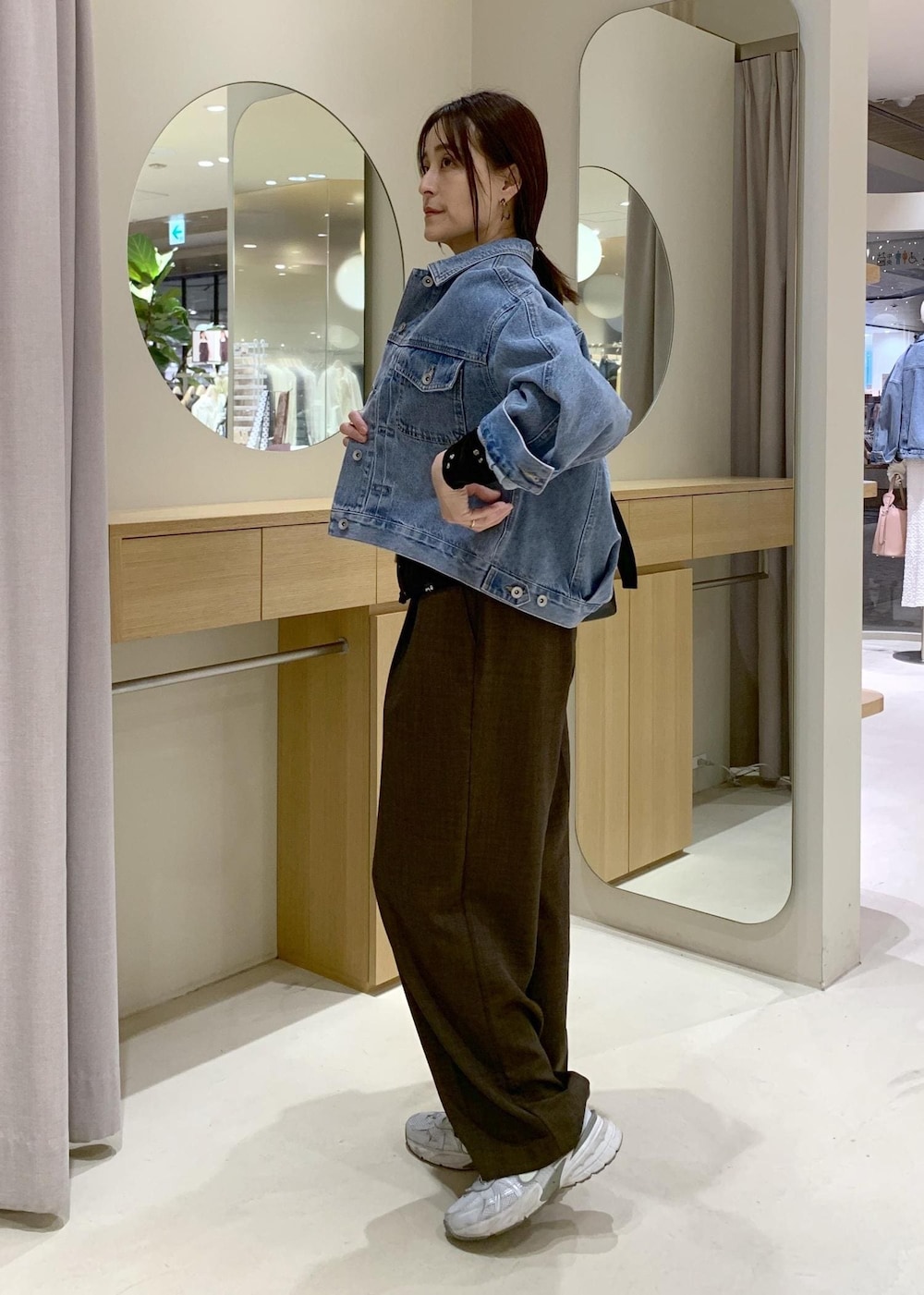 ブルー系のデニムジャケット、ブラック系のトートバッグ、ブラウン系のカーディガン/ボレロを着用したレディースの春コーディネートの2枚目の写真